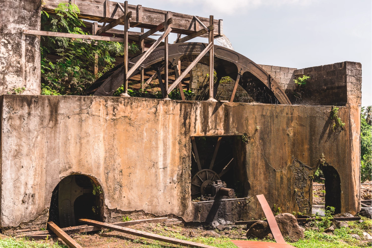 Historische Wasserrad-Zuckerrohrmühle umgeben von tropischer Vegetation
